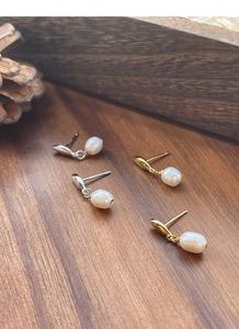 Gros plan de boucles d'oreilles perles en argent S925 et or avec poinçon sur bois