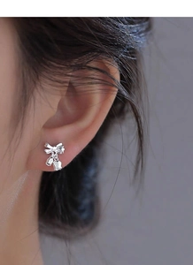 Close-up of S925 sterling silver lily of the valley bow earrings worn by a model