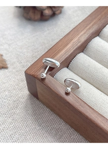 Macro shot of minimalist silver oval stud earrings featuring a screw ball back design