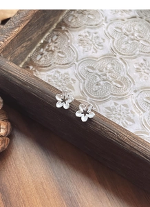 Macro shot of S925 sterling silver hollow flower studs on a vintage wooden tray