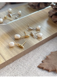 Détail de boucles d'oreilles en argent S925 et perles d'eau douce sur support en bois