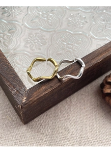 Detail of wavy S925 sterling silver rings in gold and silver finish on vintage tray