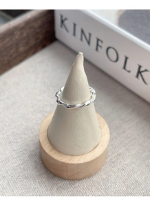 Close-up of S925 sterling silver braided ring displayed on a minimal beige jewelry stand