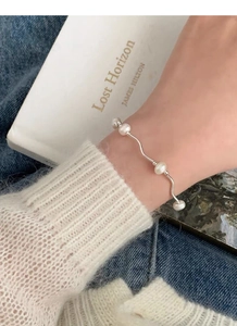 Close-up of S925 sterling silver wave bracelet with four freshwater pearls on wrist