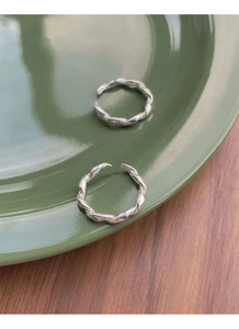 Detailed close-up of S925 sterling silver twisted rope rings on a vintage ceramic plate