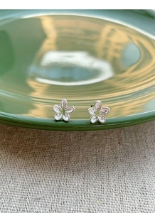 Detailed macro view of S925 sterling silver hollow flower studs with matte finish texture