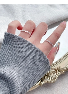 Detail of stacked S925 sterling silver hollow heart rings worn on a hand