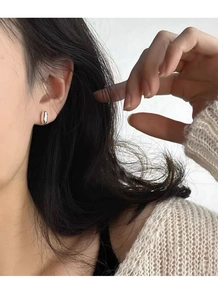 Detailed view of polished oval stud earrings in sterling silver on a female model