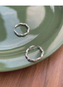 Detailed view of two S925 sterling silver twisted rings on a dark ceramic dish