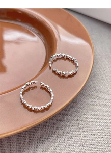 Macro view of two S925 sterling silver rings with hollow heart patterns on ceramic plate