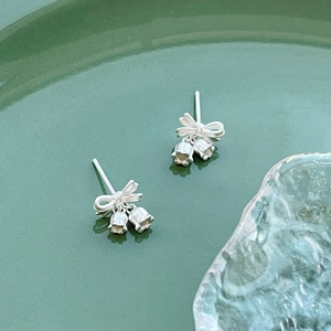 S925 silver lily of the valley bow earrings on a dark green ceramic plate