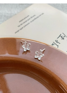 Close-up of S925 sterling silver flower stud earrings with a matte textured finish
