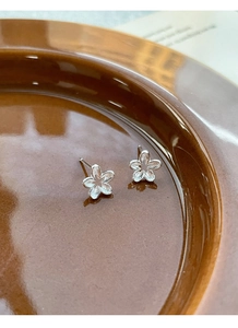 Detailed macro view of S925 sterling silver hollow flower studs with a matte brushed texture