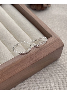 Detailed view of S925 sterling silver hollow heart rings on a walnut wood display stand