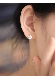 Close-up of S925 sterling silver hollow flower stud earrings worn on a model's ear