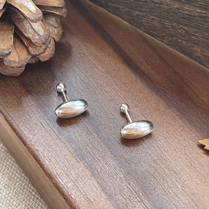 Polished S925 sterling silver oval bean stud earrings on a rustic wooden tray