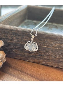 Macro detail of S925 silver ruyi lock necklace with white chalcedony on wood display