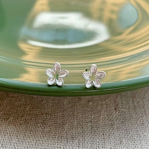Minimalist S925 sterling silver hollow flower stud earrings on a ceramic dish