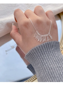 Close-up of S925 sterling silver tassel chain necklace worn on hand for elegant styling