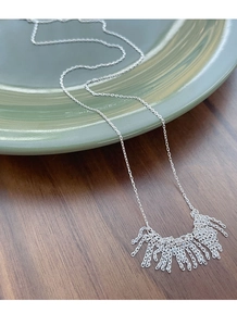 Detailed close-up of S925 sterling silver tassel necklace on a vintage ceramic plate