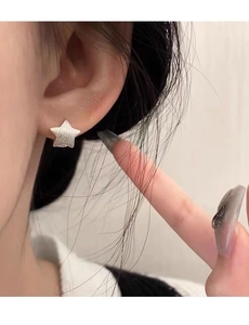 Close-up of S925 sterling silver brushed star earring stud worn on a female ear lobe