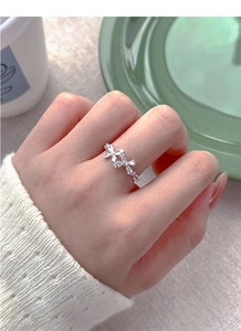 Detailed view of silver bow-shaped ring with white zircons on a model hand
