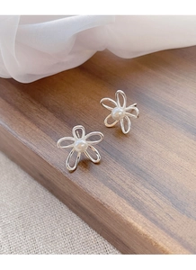 Macro di orecchini a fiore in argento con perle bianche su una superficie in legno