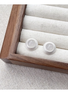 Détail de boucles d'oreilles rondes en argent S925 avec agate blanche et texture concentrique