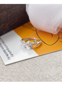 Close-up of S925 sterling silver bow ring with sparkling zircon stones on warm card