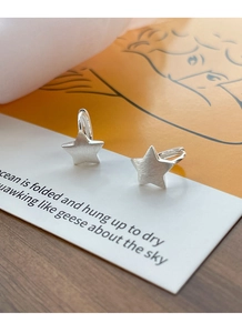 Detailed macro shot of S925 sterling silver star hoop earrings with a brushed matte texture