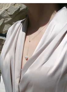 Vue macro élégante d'une perle unique sur une fine chaîne lariat en argent en forme de Y