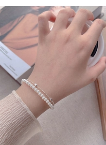 Detail of elegant double-layer silver bracelet with faux pearls and minimalist metal chain