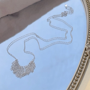 S925 sterling silver tassel necklace with delicate fringe chains on a blue mirror surface