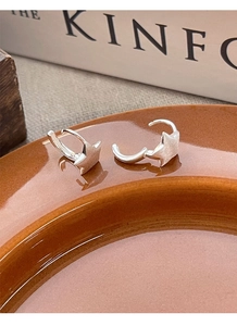 Detail of matte silver star-shaped hoop earrings on a ceramic dish with Kinfolk book