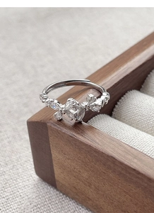 Macro shot of silver bow ring with marquise and round cubic zirconia on wood display