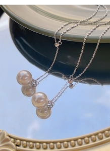Détail du collier en argent en Y avec deux perles blanches sur un miroir réfléchissant
