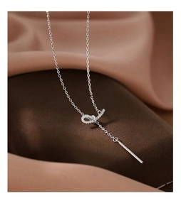 Gros plan du collier nœud en argent S925 avec zircons pavés sur fond de satin soyeux