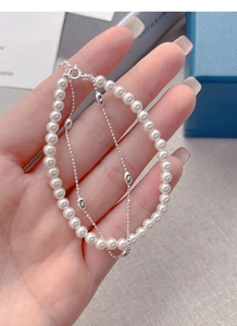Detail of double-layer S925 silver bracelet with white pearls and olive-shaped beads