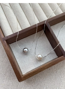 Detailed macro view of gray and white pearls on elegant silver snake chains