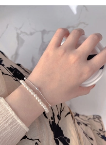 Detail view of double-layered S925 silver bracelet with pearls worn on wrist