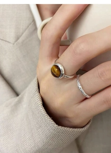 Detailed view of silver rings featuring round tiger eye stone and twisted rope texture