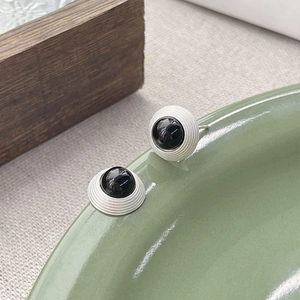 Boucles d'oreilles rondes en argent S925 avec agate noire sur une assiette céramique