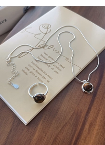 Close-up of S925 silver necklace and tiger eye stone ring set on vintage notebook