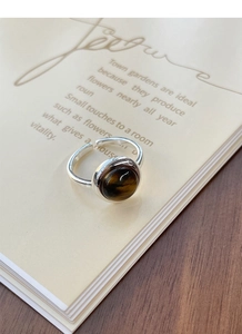 Macro detail of round tiger eye stone ring with adjustable silver band on book