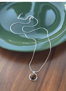 Macro shot of S925 silver snake chain with round brown tiger eye stone pendant
