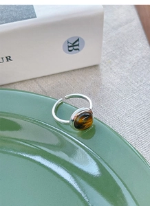 Close-up of S925 silver ring with tiger eye stone placed on a green ceramic dish