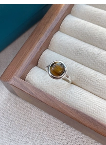 Macro shot of S925 silver ring featuring a round tiger eye stone in a wooden jewelry box