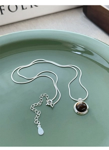 Detail of S925 silver tiger eye necklace on green ceramic tray with adjustable chain