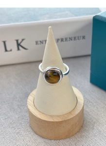 Macro shot of silver ring with round tiger eye stone on a wooden display stand