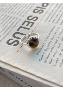 Macro detail of S925 sterling silver ring featuring a round tiger eye stone on newspaper